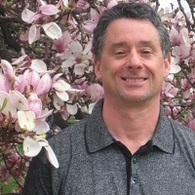 man smiling in branches of cherry tree