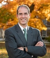 Man in suit outside against autumn trees