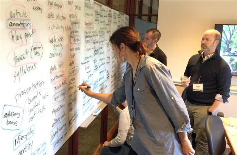 a women and two men in an office writing on a white board